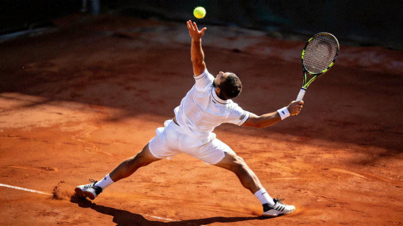 网球运动员在红土场上发球的专业姿态